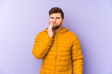 Young man isolated on purple background having a strong teeth pain, molar ache.