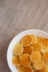 Homemade Mini Pancakes Cereal in a white bowl, top view. Flat lay, overhead, from above. Copy space.