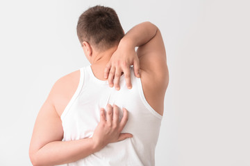 Obraz premium Teenage boy suffering from itching on light background
