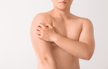 Obraz premium Teenage boy suffering from itching on light background