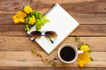 notebook planner for business work with hot coffee ,sunglasses and yellow flower of lifestyle woman relax summer arrangement flat lay style on background wooden 