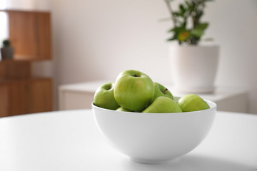 Bowl with fresh apples on table in dining room