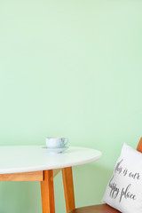 Table with chair near stylish mint wall in room