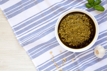 Homemade Basil Pesto with Parmesan and Pine Nuts on a white wooden background, top view. Flat lay, overhead, from above.