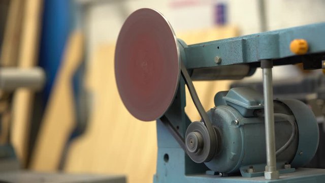 A fully functional sandpaper machine and a worker working (sanding) a piece of plastic.