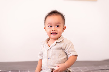 Naklejka premium Adorable asian baby boy sitting in bedroom,Happy and laughing new born kid