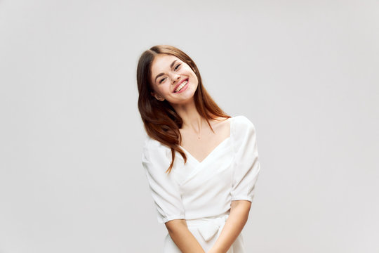 Woman with a wide smile in a white dress tilted her head to one side cropped view 