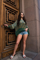 Young woman posing in trendy knitted sweater in the old city
