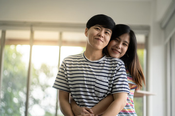 Happy asian lesbian couple hug each other with love on at living room at home,LGBTQ lifestyle...