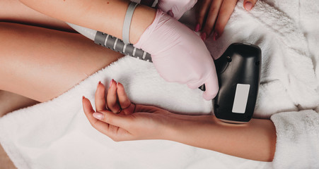 Laser epilation on hand using new devices to a caucasian woman lying on a spa couch during a procedure