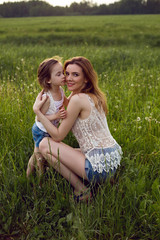 mom and daughter are sitting in a green field