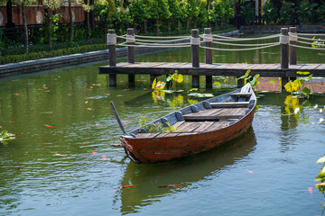 Obraz premium Wooden boat on the pond near the pier in a tropical garden in Danang, Vietnam