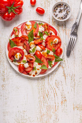Italian caprese salad with sliced tomatoes, mozzarella cheese, basil, olive oil, balsamic vinegar.