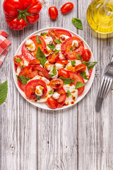 Italian caprese salad with sliced tomatoes, mozzarella cheese, basil, olive oil, balsamic vinegar.
