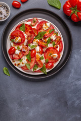 Italian caprese salad with sliced tomatoes, mozzarella cheese, basil, olive oil, balsamic vinegar.