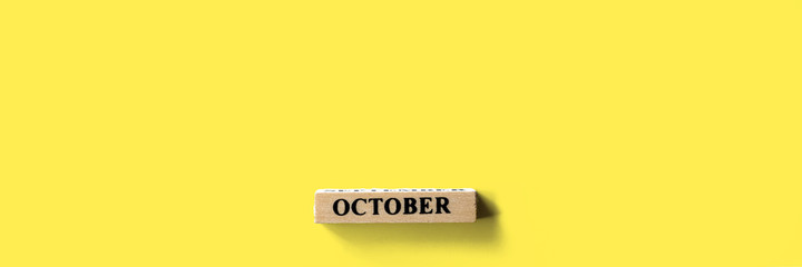 October on a wooden sign on a pastel color background.