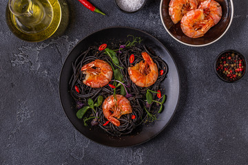 Italian pasta black spaghetti with shrimp and microgreens.