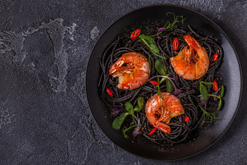 Italian pasta black spaghetti with shrimp and microgreens.