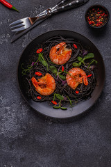 Italian pasta black spaghetti with shrimp and microgreens.