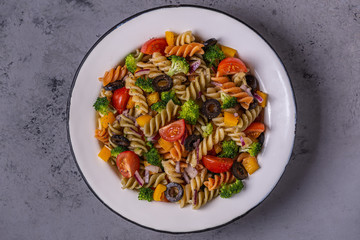Pasta salad with tomato, broccoli, black olives.