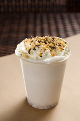 white milkshake with ice cream garnished with chocolate and nut crumbs. vertical view