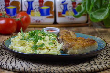 Grilled pork steak with bone in sweet honey glaze and pasta and fresh vegetables close-up on a plate on the table. horizontal