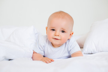 Cute baby boy smiling lies in the bed of the house. bedding for children