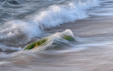 Soft Focus And Blurred Image Wave Hitting The Rock At The Beach at sunrise