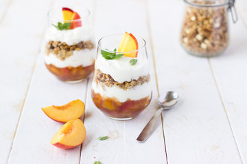 dessert glass of yoghurt, muesli and fruits on a white wooden background. summer, proper nutrition, morning, health, farming, organic food, healthy food concept. free space for text.