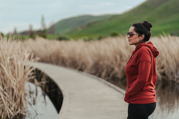 Brunette young woman wearing hoodie and sunglasses on a rural autumn landscape