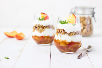 dessert glass of yoghurt, muesli and fruits on a white wooden background. summer, proper nutrition, morning, health, farming, organic food, healthy food concept. free space for text.
