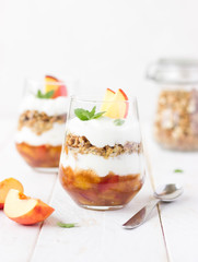 dessert glass of yoghurt, muesli and fruits on a white wooden background. summer, proper nutrition, morning, health, farming, organic food, healthy food concept. free space for text.