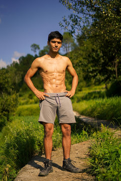 Young shredded boy standing shirtless on the pathway. Fitness and health.