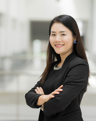 Portrait of a cheerful middle-age businesswoman in business suit standing in the company building with confidence arms crossed. Modern businesswoman in the office with copy space. stock photo.