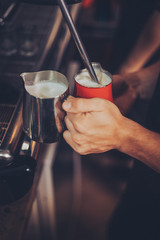 Barista preparing milk foam for cappuccino on espresso machine