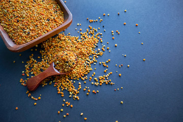 Bee pollen in a wooden spoon healthy food supplements. dark table background. ball or pellet of...