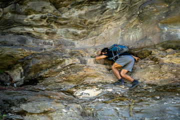 Young boy climbing the rocks wearing a backpack.