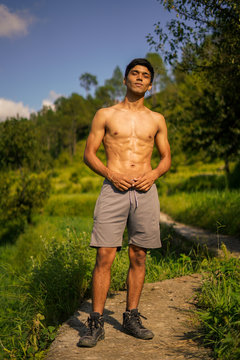 Young handsome boy standing shirtless on the pathway. Fitness and health.