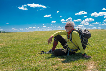 Naklejka na ściany i meble Active senior man hiker taking a break in nature overlooking the beautiful nature landscape in the background