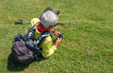 Active senior man taking a break in the nature while checking coordinates with hand held GPS navigator device