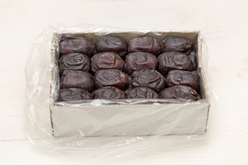Oriental dates in a cardboard box on a white background. View from above.