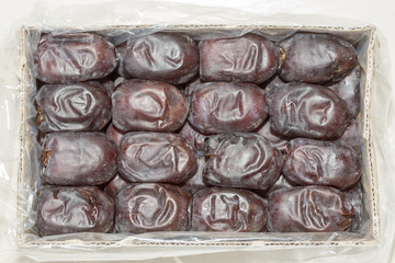 Oriental dates in a cardboard box on a white background. View from above.