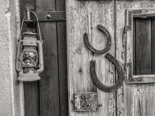 Hufeisen und Laterne an alter Hauswand, schwarz-weiß