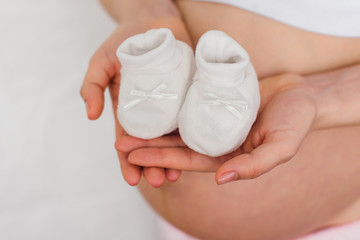 hands of a pregnant woman with booties for a newborn