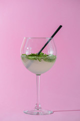 Mojito alcohol cocktail, tropical beverage with ice, mint and lime on pastel pink background with copy space.