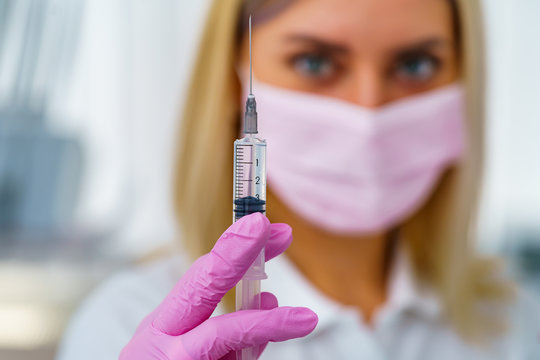 Doctor Or Nurse Hand In Pink Gloves Holding Syringe With Vaccine For A Baby Or Adult. Medicine And Drug Concept.