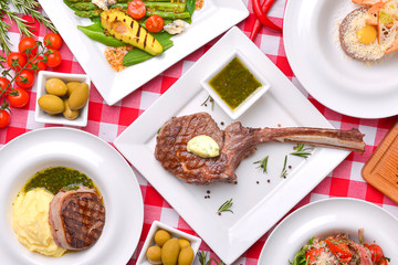 Dinner Table Concept. Italian cuisine, Italian concept. Flat lay banner. Tomahawk steak, avocado and asparagus salad.