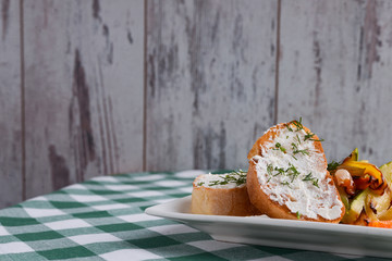 Bruschetta with cream cheese and fresh dill. Traditional Italian dish, tasty meal. Fried potatoes with vegetables.