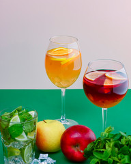 Two tropical mixed drinks, apple, mint, lime cocktails served on green and white background.