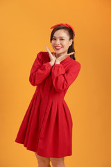 Beautiful lovely girl in red dress isolated on orange background in full body.